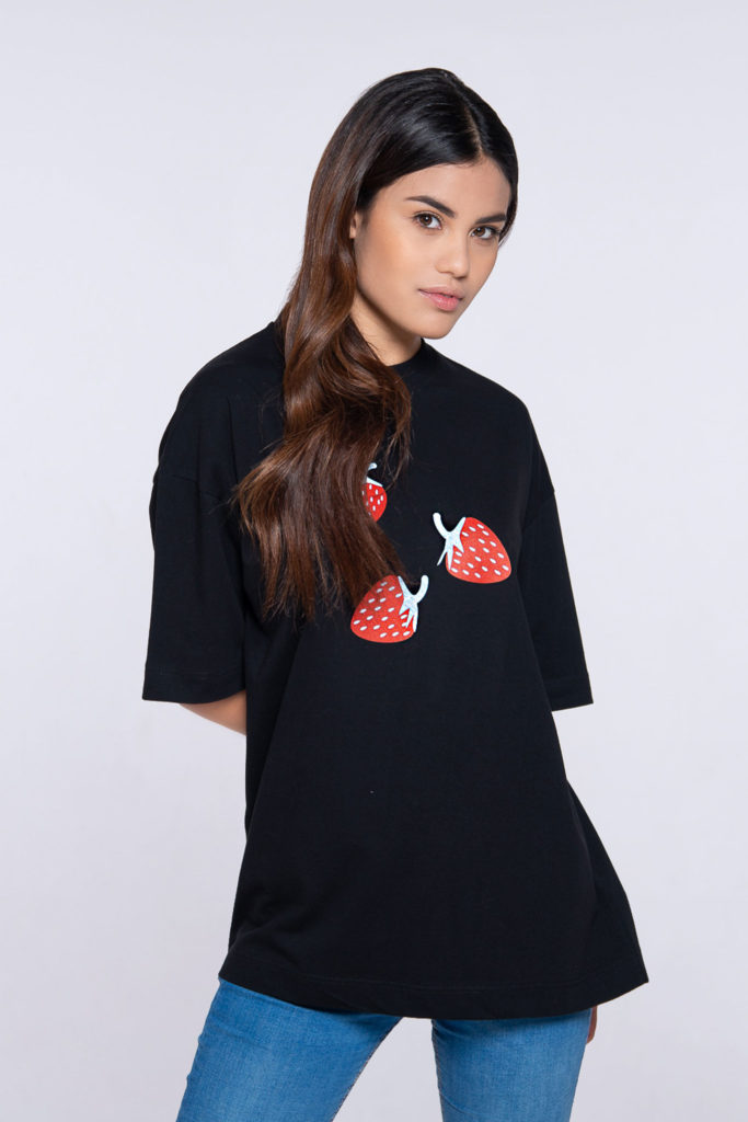 Model Sophia wearing unisex skate Short sleeves T-shirt in black featuring strawberries with signature waves pattern on front and white Everything logo at the back. Crewneck collar. Skate fit